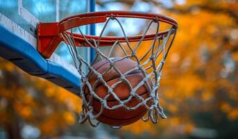 A basketball is hanging from a net in a basketball hoop. The ball is wet and he is frozen photo