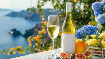 White wine in glass bottle with blank label, peaches and flowers in a ceramic pot on the background of the Mediterranean landscape photo