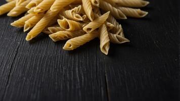 Top view of dry pasta on a black wooden surface typical of Italian cuisine creating a visually appealing copy space image. photo