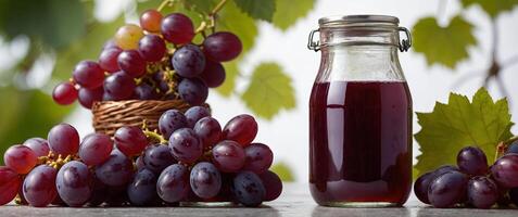 a glas jar filled with grape juice surrounded by red grapes on a white studio background. photo