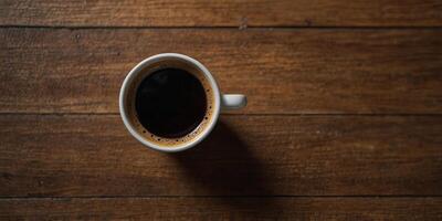 Top view of a cup of coffee displayed on a wooden surface with empty space for additional images. photo