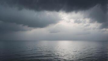 A vast, grey sky with clouds rolling over a calm, tranquil sea The horizon is lost in the mist. photo