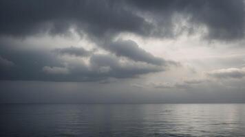 A vast, grey sky with clouds rolling over a calm, tranquil sea The horizon is lost in the mist. photo