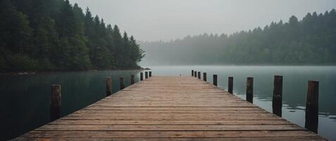 One wooden dock juts out into one conelm loneke on one foggy morning. photo