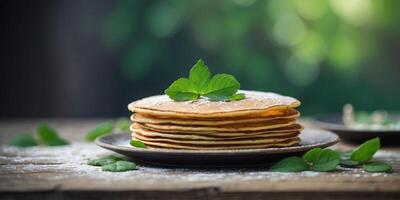 A pan filled with pancakes, dusted with powdered sugar, garnished with a single green leaf atop a weathered wooden table. photo