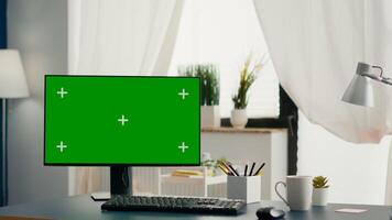 Empty bright living room with isolated mock-up green screen chroma key monitor standing on desk. Home office with nobody lying on is ready for business network photo