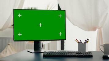 Powerful computer with chroma key green screen mock up stands on desk in living room. Pc with isolated display in home office with nobody in is ready for online business meeting photo