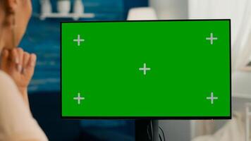 Close up of woman having videocall conference on personal computer with mock up green screen chroma key sitting at home office space. Business female working with teammates using isolated pc photo