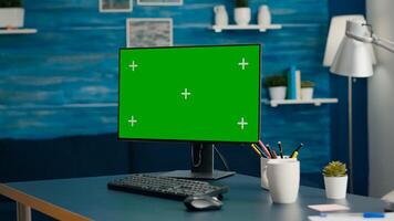 Close up of professional powerful computer with mock up green screen chroma key standing on table in bright living room with nobody in it. Pc with isolated display is ready for online business photo