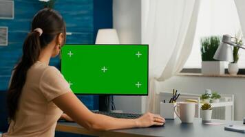 Business woman typing on professional computer with mock up green screen chroma key sitting at modern office desk. Female working at marketing project on pc with isolated display photo