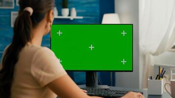 Woman sitting at office desk and searching on internet for commerce business using computer with mock up green screen chroma key. Caucasian female working with isolated pc photo