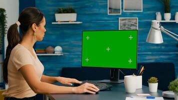 Caucasian woman working on powerful computer with mock up green screen chroma key sitting on desk. Freelancer searching information for business project using isolated pc photo
