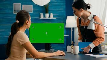 Busniess woman talking with young collegue about internet network showing on computer with mock up green screen chroma key. Caucasian female using isolated desktop pc in home office photo