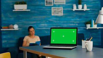 Woman sitting on desk table working on business commerce using isolated laptop computer with mock up green screen chroma key. Caucasian female typing on pc in home office studio photo