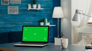 Laptop computer with mock up green screen chroma key display standing on table in living room. PC with isolated display in home office studio with nobody in it photo