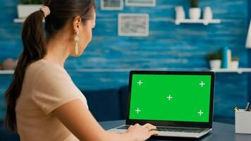 Business woman looking at laptop display with mock up green screen chroma key while working at network communication. Freelancer sitting on desk in office studio using powerful isolated pc photo