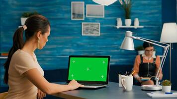 Freelancer using computer with mock up green screen chroma key for business company standing on desk table. Woman using isolated home office pc working at commerce project in home office photo