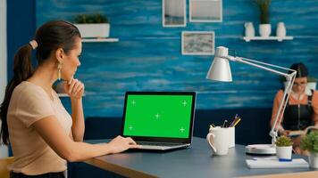 Woman working at businees project for company using laptop computer with mock up green screen chroma key. Caucasian freelencer using isolated pc while standing in home office studio photo