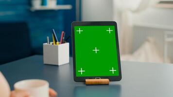 Close up of tablet computer with mock up green screen chroma key display it is used for office work. Freelancer woman working on communication project using isolayed gadget sitting on desk photo