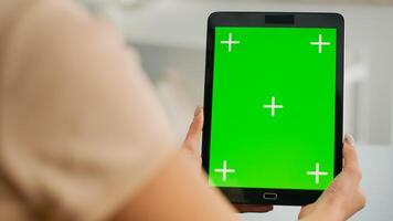 Close up of woman hands holding tablet computer with mock up green screen chroma key display. Freelancer sitting on office desk in living room working with isolated device for online lifestyle project photo