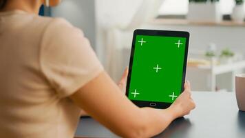 Freelancer woman holding tablet computer with mock up green screen chroma key display sitting on office room. Caucasian female browsing on internet for online project using isolated device photo