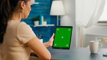 Freelancer woman working on communication ideas for online project using tablet computer with mock up green screen chroma key display. Office room in equipped with powerful isolated device photo