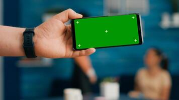 Front view of horizontal isolated mock up green screen chroma key display of modern phone. Two collegues talking about internet browsing and social media in home studio background photo