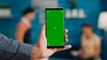 Pov of business man hands holding professional smartphone in portrait vertical mode with mock up green screen chroma key display. Freelancer using isolated phone for browsing social networks photo