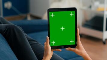 Close up of business woman hands holding tablet computer with mock up green screen chroma key display sitting on sofa. Freelancer using isolated touchscreen device for social networks browsing photo