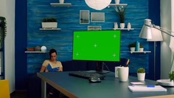 Freelancer working on powerful computer with mock up green screen chroma key display sitting on desk table. Caucasian female looking for business nformation on network using isolated pc photo