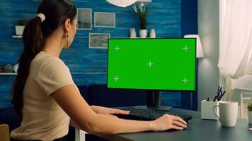 Woman working at business connection with teammates on computer with mock up green screen chroma key display sitting at desk table. Freelancer browsing on network with isolated pc photo