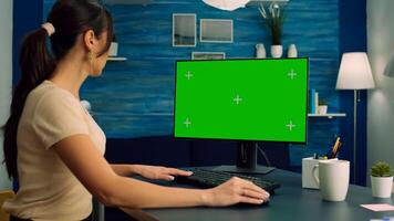 Freelancer looking for marketing information on internet using personal computer with mock up green screen chroma key. Business woman working with isolated pc at office desk in living room photo