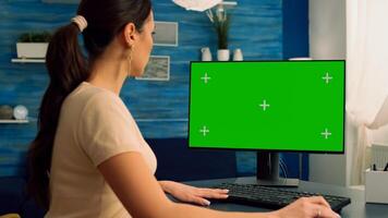 Business woman browsing on computer with mock up green screen chroma key display looking for online advertising sitting at desk table. Freelancer using isolated pc in home office photo