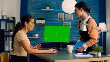 Teammates talking about business communication working on computer with mock up green screen chroma key display. Office home is equipped with isolated pc, standing on table desk photo