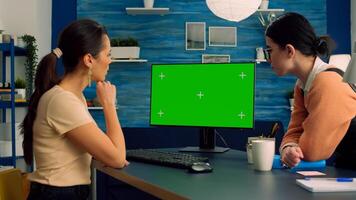 Two collegues working together on computer with mock up green screen chroma key display for social media advertising. Teammates looking at isolated pc sitting at desk table in home office photo