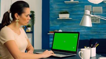 Business woman working at online coomunication project using laptop computer with mock up green screen chroma key display. Caucasian female standing on table desk working with isolated pc photo