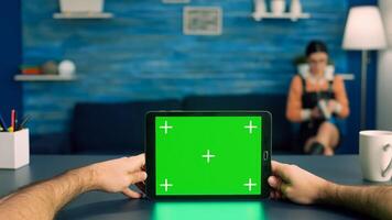 Point of view of business man hands holding tablet computer with mock up green screen chroma key display standing on desk table. Caucasian male using isolated device for digital advertising photo
