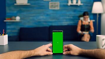 Point of view freelencer man in office studio holding mock up green screen chroma key phone. Caucasina female browsing on internet using isolated device for social media connection photo