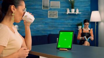 Freelancer woman browsing on internet business advertising using isolated device standing in home office studio. Caucasian female working with tablet computer with mock up green screen chroma key photo