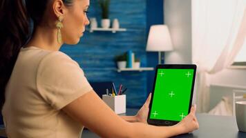 Business woman having online videocall with treamates uses tablet computer with mock up green screen chroma key display. Freelancer using isolated device for advertising project standing at office photo