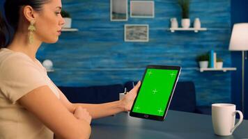 Caucasian woman looking at tablet computer with mock up green screen during online videocall . Freelancer looking at template chroma key isolated device using technology internet. photo