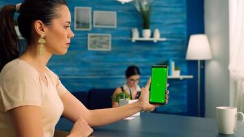 Business woman sitting on office table in living room using modern phone with mock up green screen chroma key with trackpoints. Freelancer browsing on internet for social media content photo