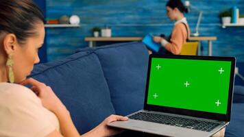Business woman searching lifestyle advertising using isolated pc lying on sofa in living room. Caucasian female working with laptop computer with mock up green screen chroma key photo