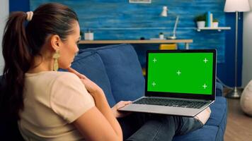 Back shot of caucasian female typing and looking at laptop computer with mock up green screen chroma key. Business woman searching the web for company information using isolated pc photo