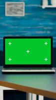 Laptop computer with mock up green screen chroma key standing on desk while in background two women talking about business commerce. Home studio is eqquiped with powerful isolated pc photo