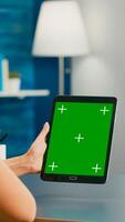 Freelancer woman working on communication ideas for online project using tablet computer with mock up green screen chroma key display. Office room in equipped with powerful isolated device photo