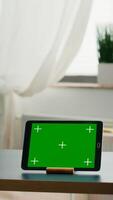 Two collegues talking about internet connection in front of tablet computer with mock up green screen chroma key. Women browsing on isolated device sittings at office desk in modern living room photo