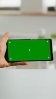 Freelancer holding smartphone with mock up green screen chroma key in horizontal position. Business woman searching online information using isolated device sitting on office desk photo
