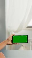 Business woman holding phone with mock up green screen chroma key for copy space sitting on office desk. Social media influencer browsing on internet using isolated gadget photo