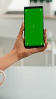 Business woman browsing on internet using mock up green screen chroma key smartphone sitting at office desk. Freelancer swiping online information for social media project using isolated device photo